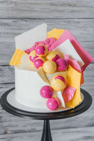 Stylish colored cake staying on black tray on the white wooden background. Birthday party...