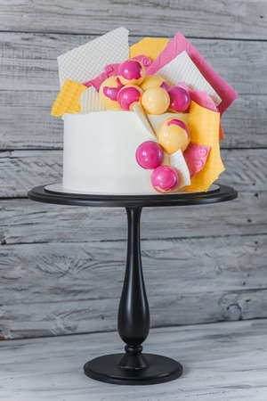 Stylish colored cake staying on black tray on the white wooden background. Birthday party celebration gift.の写真素材
