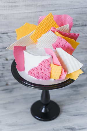 Stylish colored cake staying on black tray on the white wooden background. Birthday party celebration gift.の写真素材