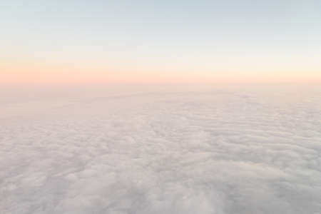 Airplane illuminator view on fluffy clouds and sunrise sky. Clouds view from the aircraft illuminatorの写真素材