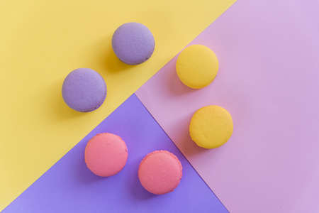 Sweet tasty violet, pink and yellow french macaron cakes on multicolored background.の写真素材