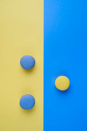 Sweet tasty blue and yellow french macaron cakes on yellow and blue background.の写真素材