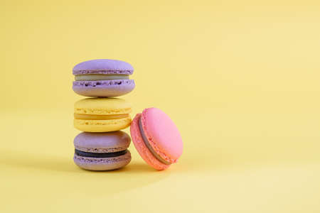 Tasty violet and yellow french macaron cakes on yellow background.の写真素材