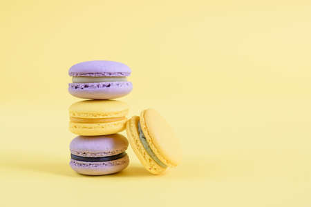 Tasty violet and yellow french macaron cakes on yellow background.の写真素材