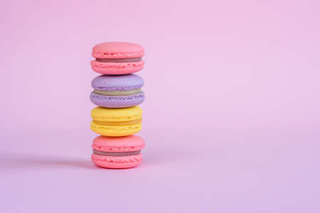 Tasty violet, pink and yellow french macaron cakes on pink background.の写真素材