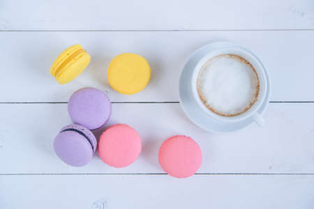 Sweet delicious colorful macarons and cup of coffee on white wooden background.の写真素材