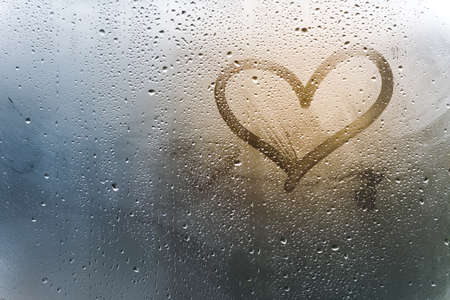 Rainy weather, the inscription heart on the sweaty glassの写真素材