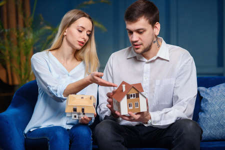 Cute caucasian man and woman discussing two model of 3d maket of house.の写真素材