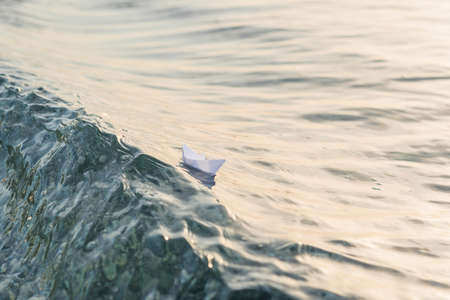 Paper boat sailing on the crest of the waves in the seaの写真素材