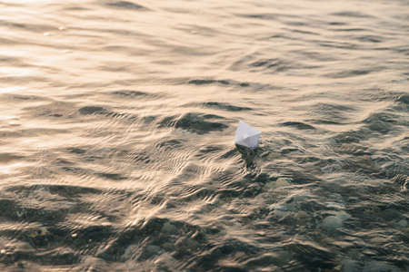 Origami white paper boat on blue deep water.の写真素材