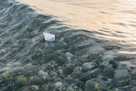 Paper boat sailing on the crest of the waves in the sea