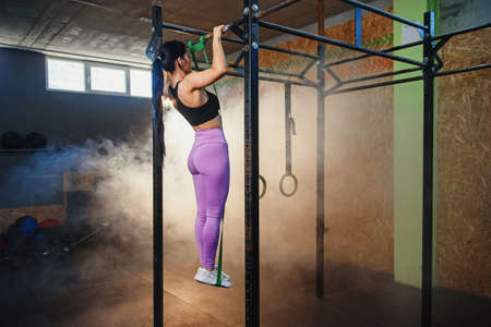 Strong fit woman doing pull up on horizontal bar.