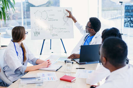 Professional group of multi racial doctors or interns with mentor have a meeting and making notes at...
