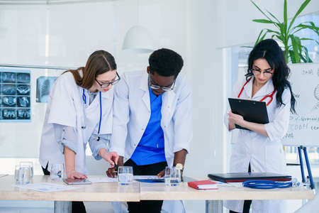 Professional team of doctors discussing patients x-rays results. Multi ethnic group of medical students discuss patients diagnosis.の写真素材
