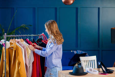 Young attractive smiling woman searching what to wear in a wardrobeの写真素材