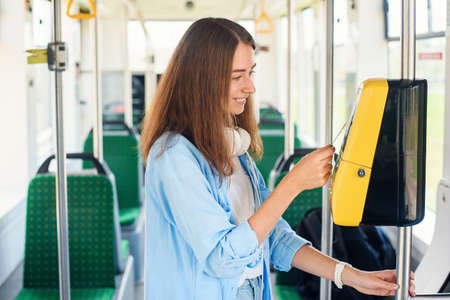 Young woman pays by bank card for the public transport in the tram or subway.