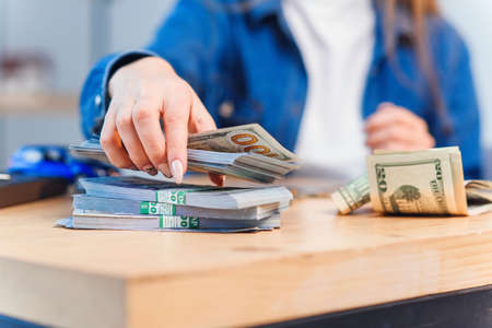 Beautiful young woman counts money savings to buy her own vehicle.
