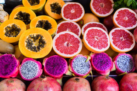 Exotic summer fruits laid out in shopping mall or market. Dragon fruit, pineapple, persimmon, mango,...