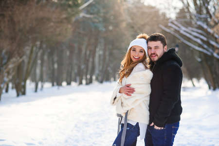 Beautiful couple in love hugging each other while walking in a winter Park.の写真素材