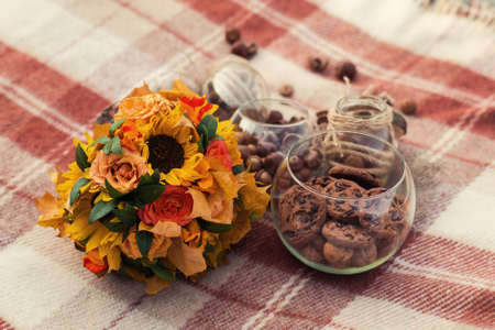 Autumn vintage decorations. Glass jars with ropes, acorns, cookies and autumn bouquet on brown...