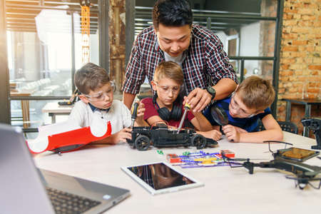 Male electronic engineer with european school children working in smart school lab and testing model of radio controlled electric car.の写真素材