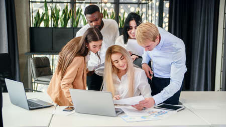 Close up of successful young mixed race work team analysing financial report during their work under...