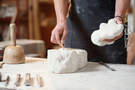 Craftsman hands working with stone sculptor at creative workplace in the atmospheric studio.の写真素材