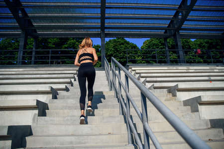 Young woman runner sportswoman climbing up city stairs jogging and running in urban training workout