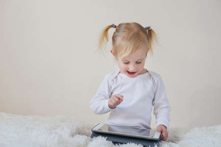 Adorable happy little girl with tablet pc computer at home.の写真素材