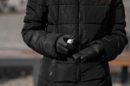 Beautiful girl stays behind the table with health face protection mask against COVID-19, Coronavirus, spraying disinfection liquid on surgical gloves and waiting for passengers at the Belgrade Airportの写真素材