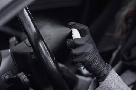 Cleansing car interior and spraying with disinfection liquid. Hands in rubber protective glove disinfecting vihicle inside for protection from virus diseaseの写真素材