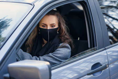 Woman in the city. Person in a mask. Coronavirus theme. Woman by the car.