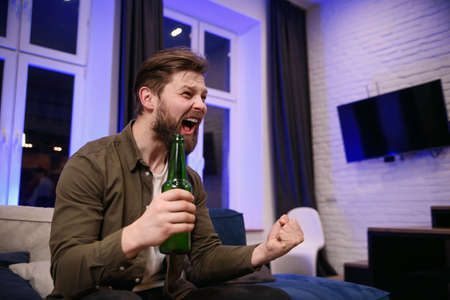 Portrait of good-looking modern attantive young guy with well-maintained beard which rejoicing the...