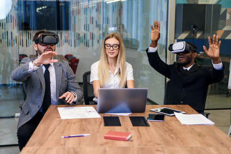 Business people using virtual reality goggles during meeting. Team of developers testing virtual...