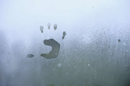Little child's handprint on foggy glass. Bad weather and depression concept.
