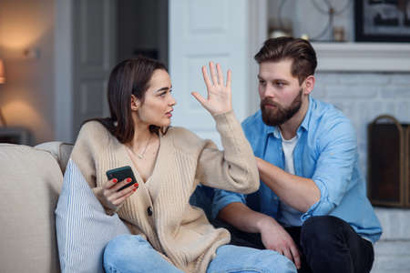 Modern couple at home. Man and woman concentrated on messaging with smartphones, ignoring each other...