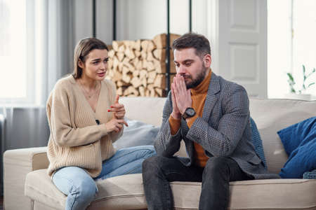 Upset young couple after quarrel at homeの写真素材