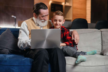 Grandson is teaching his grandfather to use laptop computer.