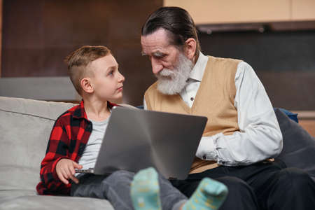 Grandson is teaching his grandfather to use laptop computer.