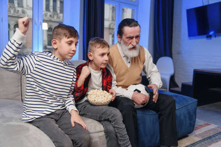 Likable concentrated senior bearded grandfather with his cheerful 10-15s grandsons spending their...