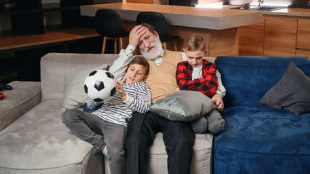 Excited three generations of men sport fans relax in living room celebrate team victory together,...