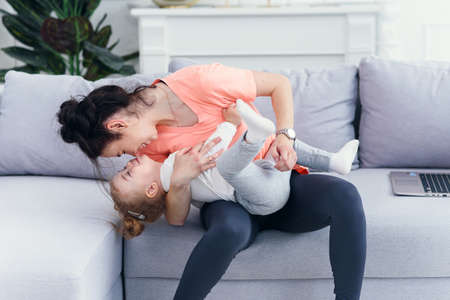 Young beautiful mother having fun with her toddler daughter at cozy home.の写真素材