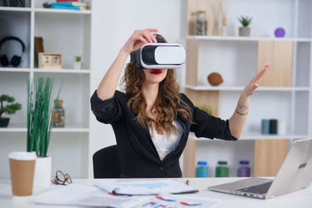 Confident modern business lady in stylish clothes which using 3d virtual reality goggles at her office.の写真素材