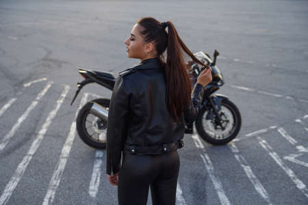 girl with long hair in a leather jacket in an underground parking lot on a motorcycle