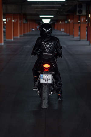 Lviv, Ukraine - 01.07.2020: A girl in black protective gear in an underground parking lot on a Honda...