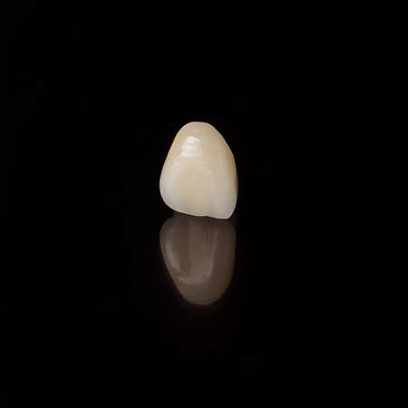 Highly-quality dental crown on a black background, close up tooth morphology.
