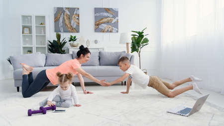 Sports mom with son doing morning work-out at home. Mum and son do exercises together, healthy family lifestyle conceptの写真素材