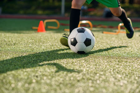 Soccer player kicking ball on field. Soccer players on training session. Close up footballer feet...