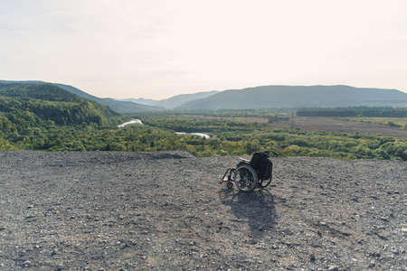 Medical wheelchair being on knoll on the backdrop of beautiful nature and high mountains....