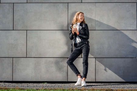 Beautiful happy girl with cold fresh smoothie outdoors. Smiling hipster girl with cup of milkshake...